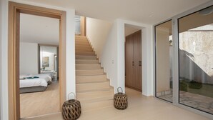 Habitación de hotel moderna con una escalera, cama con vistas y puerta de cristal que da a un espacio exterior.