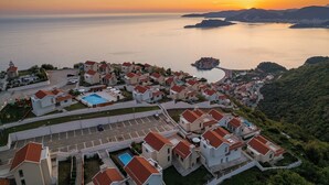 Zona residencial costera con casas, piscina y vistas al mar y a las montañas.