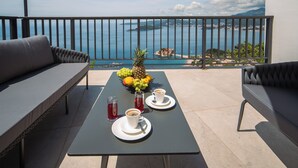 Un balcón con una mesa preparada para dos personas, un frutero y dos tazas de café.