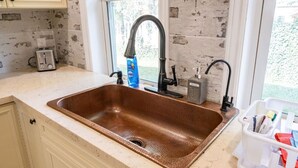 A kitchen with a copper sink, a window, a toaster, and a soap dispenser. - Stylish Urban Escape - Close to DTK and Expwy (Kitchener)