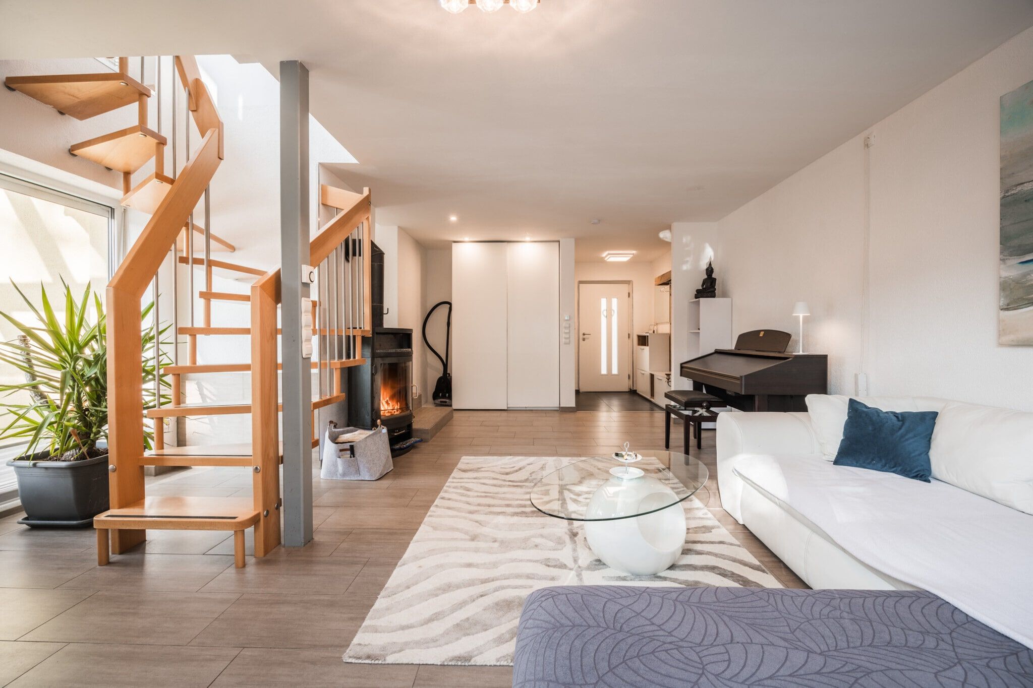 Ein modernes Wohnzimmer mit Treppe, Kamin, Klavier und einer Couch.