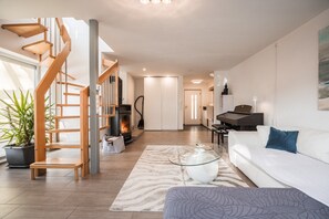 A modern living room with a staircase, a piano, a sofa, and a coffee table.