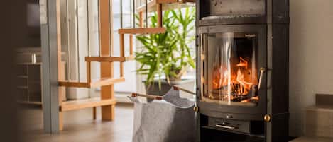 A modern interior with a wood-burning stove, a bench, and a potted plant.