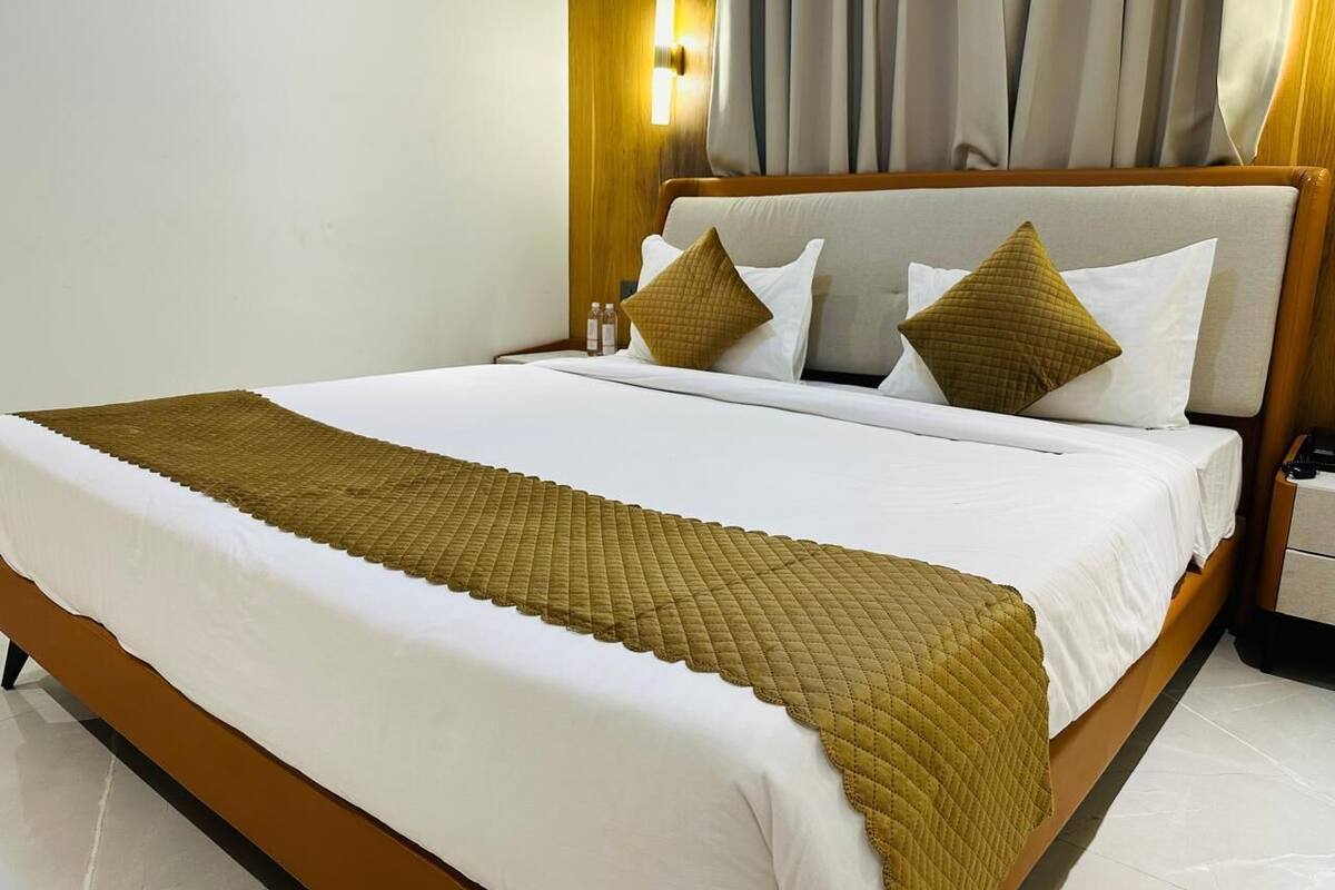 Una cama bien tendida con una colcha acolchada, un cabecero de madera y una mesita de noche con una lámpara.