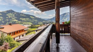 Un balcón de madera con vistas a verdes colinas y montañas.