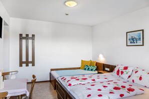 A bedroom with a bed, bedside table, chair, and a wall-mounted light fixture.