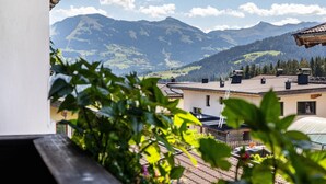 Une vue sur la montagne depuis un balcon doté d’une balustrade en bois, un ciel dégagé et un bâtiment avec un toit en pente.