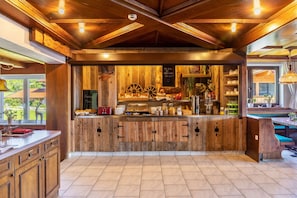 A rustic kitchen with wooden cabinets, a central island with food items, and a chalkboard menu. - Room '11' with Mountain View, Shared Terrace and Wi-Fi (Hopfgarten im Brixental)