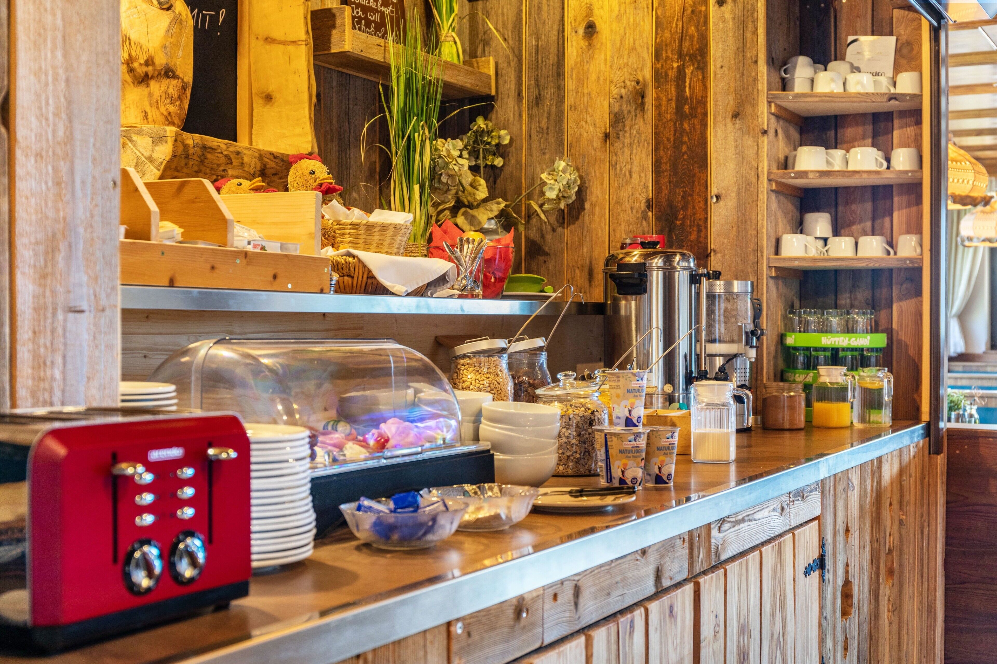 Un bar pour le petit-déjeuner équipé d’une machine à café, de bols et d’un appareil de couleur rouge.
