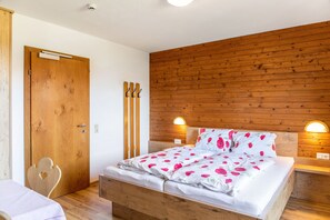 Een kamer met houten lambrisering, een bed, een houten deur en een kapstok.