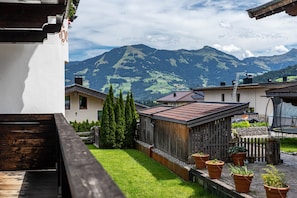 Un patio con piso de madera, plantas en macetas y vistas a las montañas.