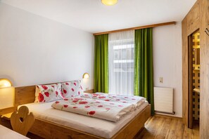 Un dormitorio con cama de madera, cortinas verdes, radiador blanco y puerta de madera.