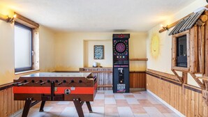 Ein Raum mit einem Tischfußballtisch, einer Dartscheibe und einer Dart-Maschine.