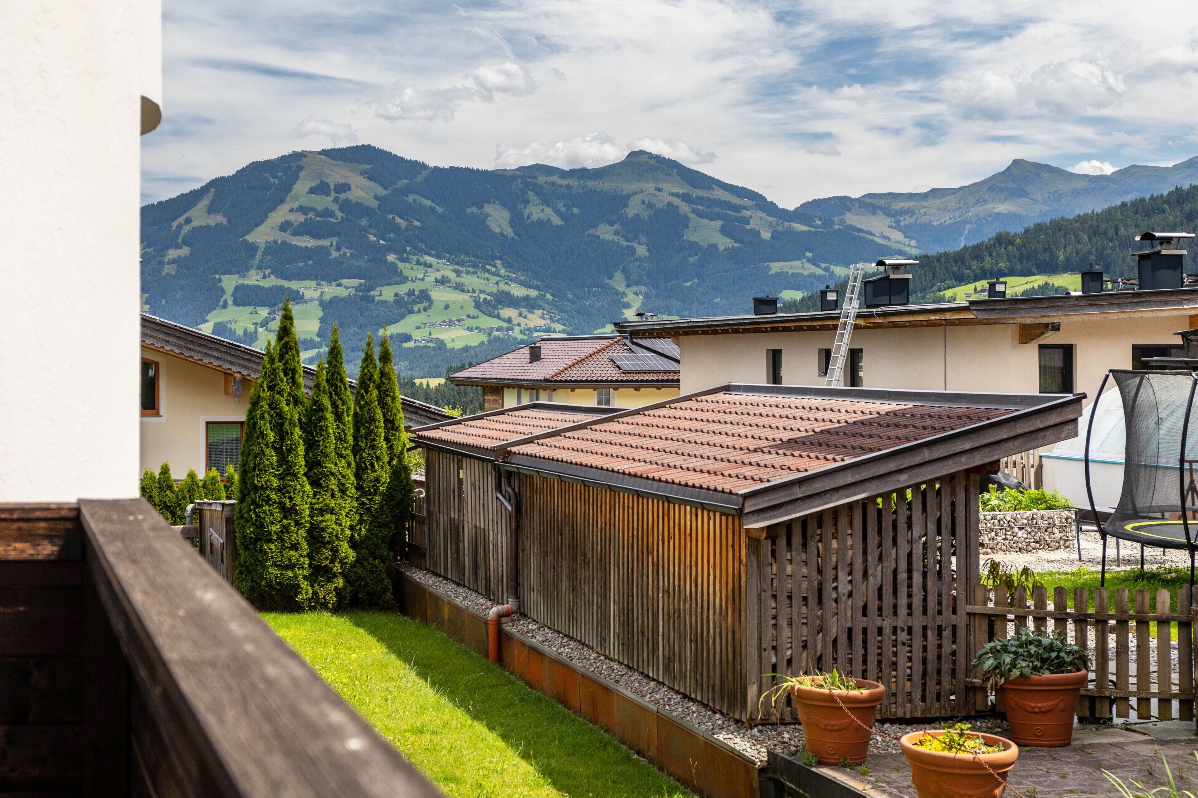 Ein Wohngebiet mit Holzzaun, Kübelpflanzen und Blick auf Berge.