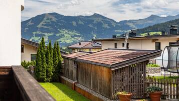 Ein Wohngebiet mit Holzzaun, Kübelpflanzen und Blick auf Berge.