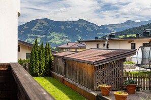 Un barrio residencial con cerca de madera, plantas en macetas y vistas a montañas.
