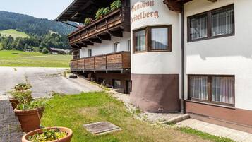 Ein Gebäude mit Balkon, einem Schild mit der Aufschrift 'Pension Gaisberg' und Blick auf eine grüne Landschaft.
