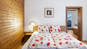 A bedroom with a wooden slat wall, a bed with floral bedding, a bedside lamp, and a framed picture on the wall.