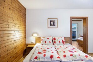 A bedroom with a wooden slat wall, a bed with floral bedding, a bedside lamp, and a framed picture on the wall.