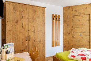Ein Schlafzimmer mit Holzschränken, einem Bett mit grüner Matratze und einem an der Wand befestigten Skiregal.