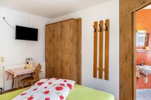 Une chambre à coucher comprenant un lit, un bureau, une chaise, une armoire et un téléviseur fixé au mur.
