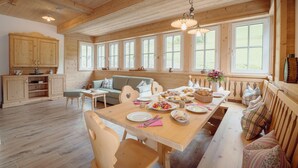 A wooden interior with a dining table set for a meal, a sofa, and a bench with cushions.