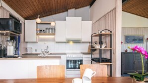 Une cuisine moderne avec des meubles blancs, un plan de travail en bois et un coin repas comprenant une table et des chaises en bois.