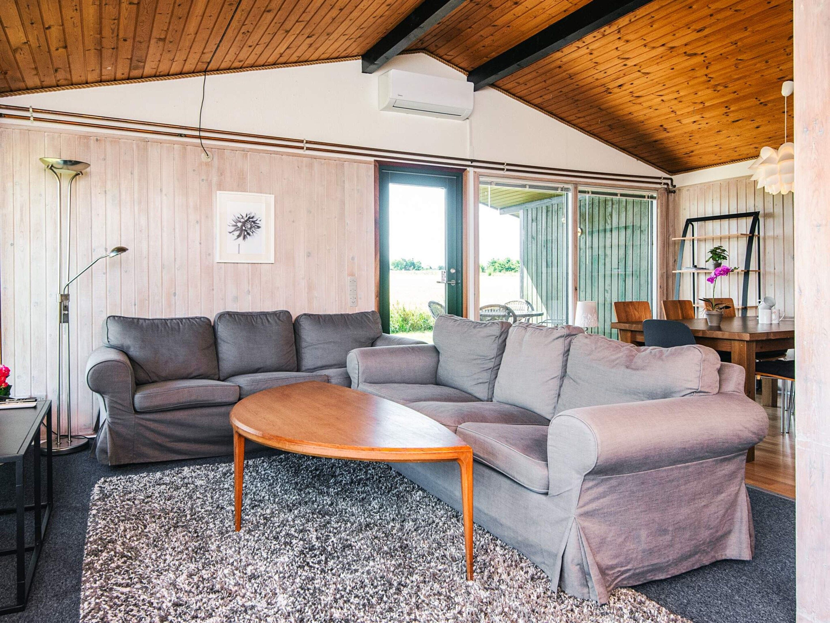 Una sala de estar moderna con un sofá seccional, una mesa de centro de madera y un ventanal que proporciona luz natural.