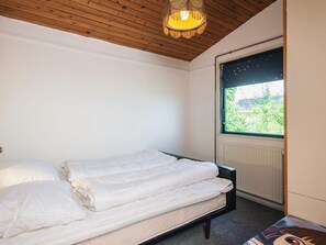 A bedroom with a bed, a window with a view of greenery, and a wooden ceiling. - 6 Person Holiday Home in Juelsminde (Horsens)