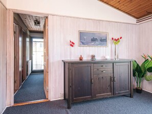 A room with a wooden cabinet, a painting, a flag, and a potted plant. - 6 Person Holiday Home in Juelsminde (Horsens)