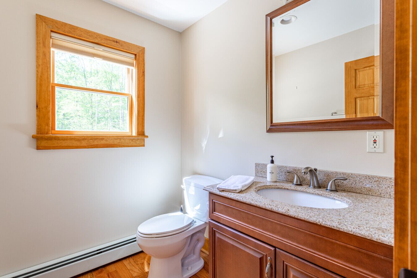 A bathroom with a toilet, sink, and window.