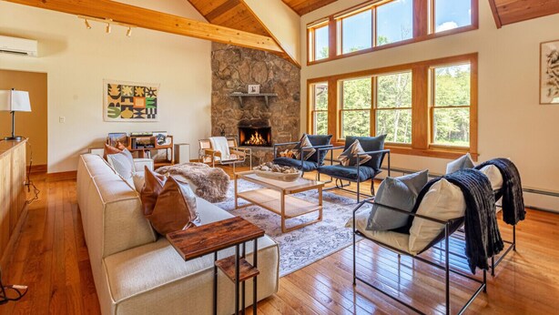 A spacious living room with a stone fireplace, wooden beams, and large windows. - NEW: Multi-Generational Haven nr Roscoe (Roscoe)