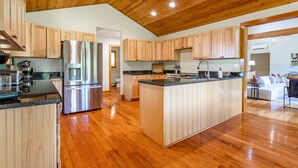 A modern kitchen with wooden cabinets, a stainless steel refrigerator, and a central island with a sink. - NEW: Multi-Generational Haven nr Roscoe (Roscoe)
