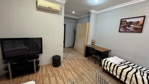 A modern living room with a flat-screen TV, a sofa, a small table, and a desk. - Arena Hotel Goychay (Goychay)