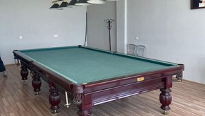 A pool table in a room with wooden flooring and a ceiling light fixture. - Arena Hotel Goychay (Goychay)