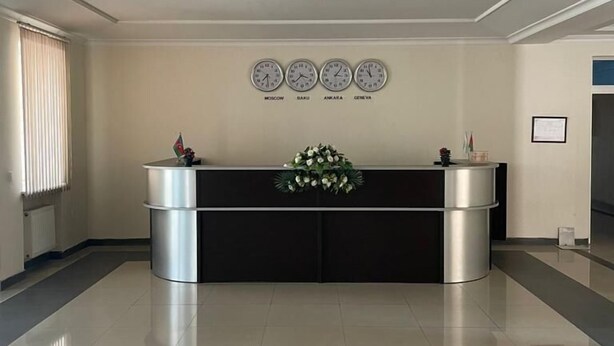 A reception desk with clocks displaying Moscow, Baku, Ankara, and Geneva times. - Arena Hotel Goychay (Goychay)