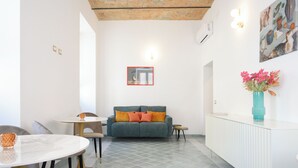 A modern living room with a sofa, a dining table, and a white console table. - Magnoliahome Suites at the Vatican (Rome)