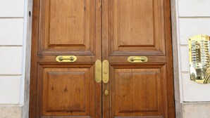 A wooden double door with brass handles and a brass threshold. - Magnoliahome Suites at the Vatican (Rome)