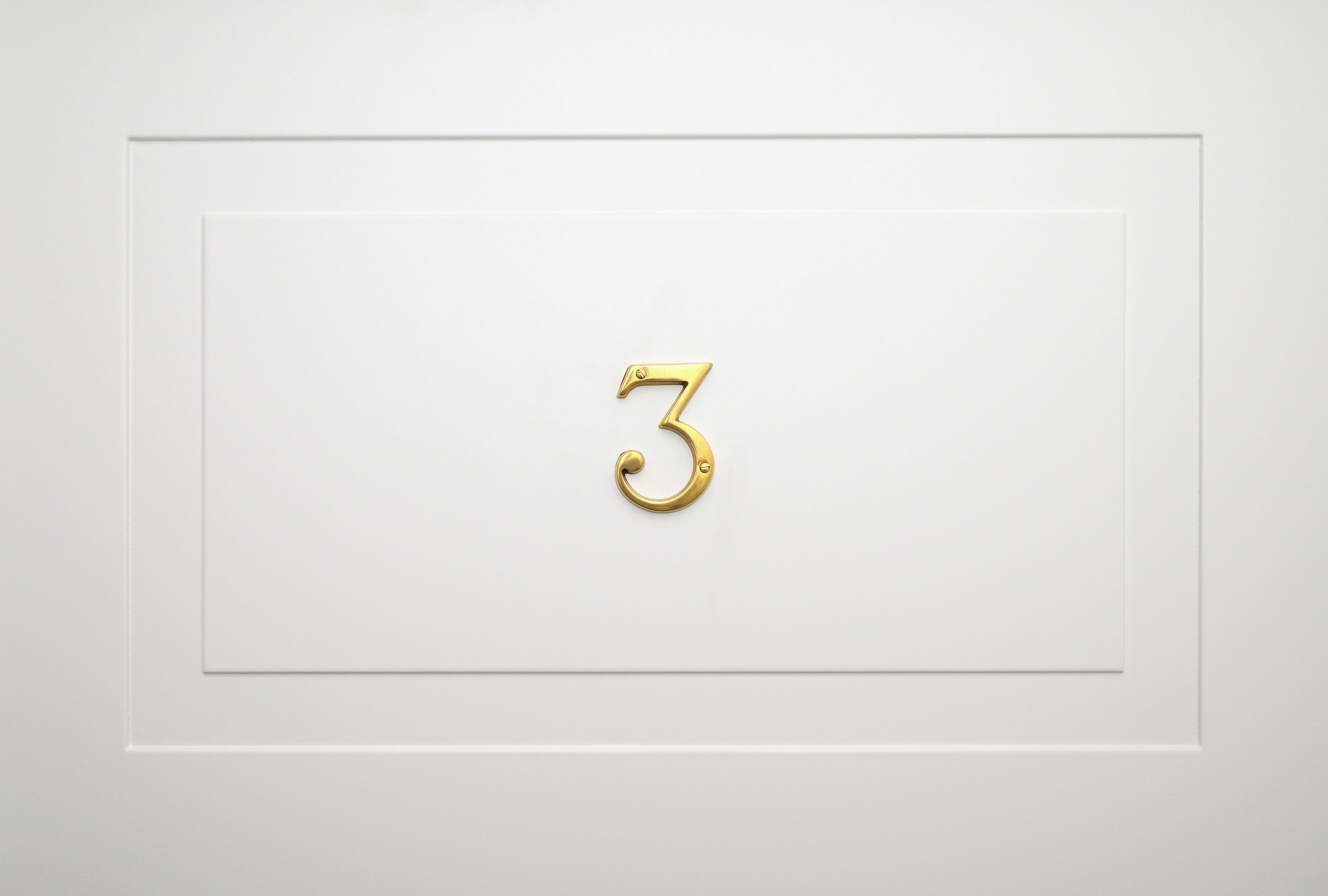 A white door with a gold number "3" handle.
