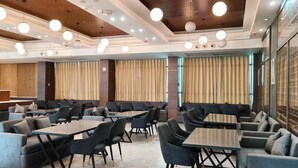 A modern dining area with round tables and cushioned seating, wooden ceiling panels, and recessed lighting. - Clarks Inn Express Firozabad (Firozabad)
