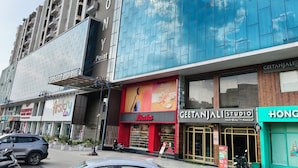 A modern building with a prominent 'First' sign, a 'Bata' store, and a 'Geetanjali Studio' hair and beauty makeup shop. - Clarks Inn Express Firozabad (Firozabad)