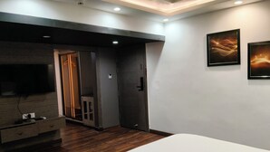 A modern bedroom with a large bed, a TV mounted on a wooden panel, a wardrobe, and two abstract paintings on the wall. - Clarks Inn Express Firozabad (Firozabad)