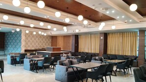 A spacious indoor area with multiple seating arrangements, including tables and sofas, and a reception desk. - Clarks Inn Express Firozabad (Firozabad)