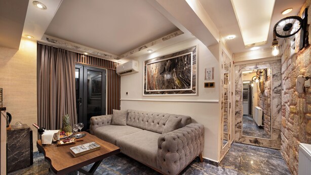 A modern living room with a sofa, a wooden coffee table, and a large mirror. - REN PLUS SUİTES OTEL (İstanbul)