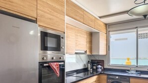 Ett modernt kök med vitvaror i rostfritt stål, träinredning och en inbyggd tvättmaskin.