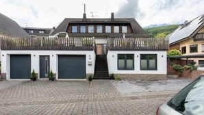 A two-story house with a front entrance, two garage doors, and a staircase leading to the upper floor. - Apartment 'Moselglück' with Mountain View, Wi-Fi and Air Conditioning (Sankt Aldegund)
