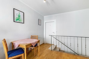 A room with a wooden table, a chair, a staircase with a metal railing, and a door marked with the number 1.