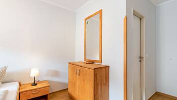 Ein Schlafzimmer mit einem Holzschrank, einem Nachttisch mit Lampe, einem Spiegel und einer Tür.