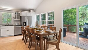 A spacious kitchen with white cabinets, a stainless steel refrigerator, and a dining area with wooden chairs and a large table.