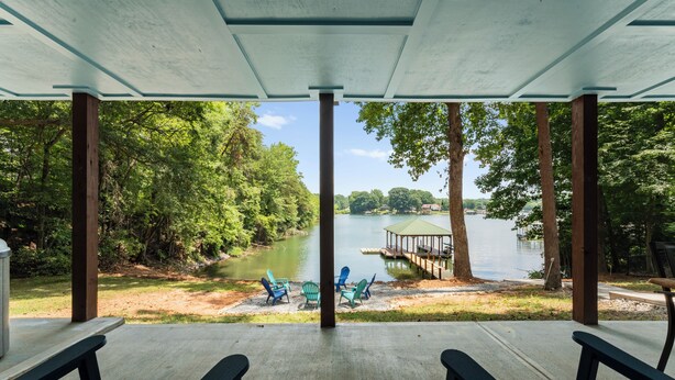 A covered outdoor seating area with a view of a lake and dock.